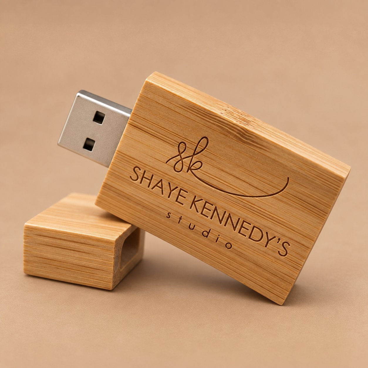 Wooden USB drive engraved with a fine-line script logo and a small studio tagline below the wordmark, demonstrating legibility of thin script strokes.