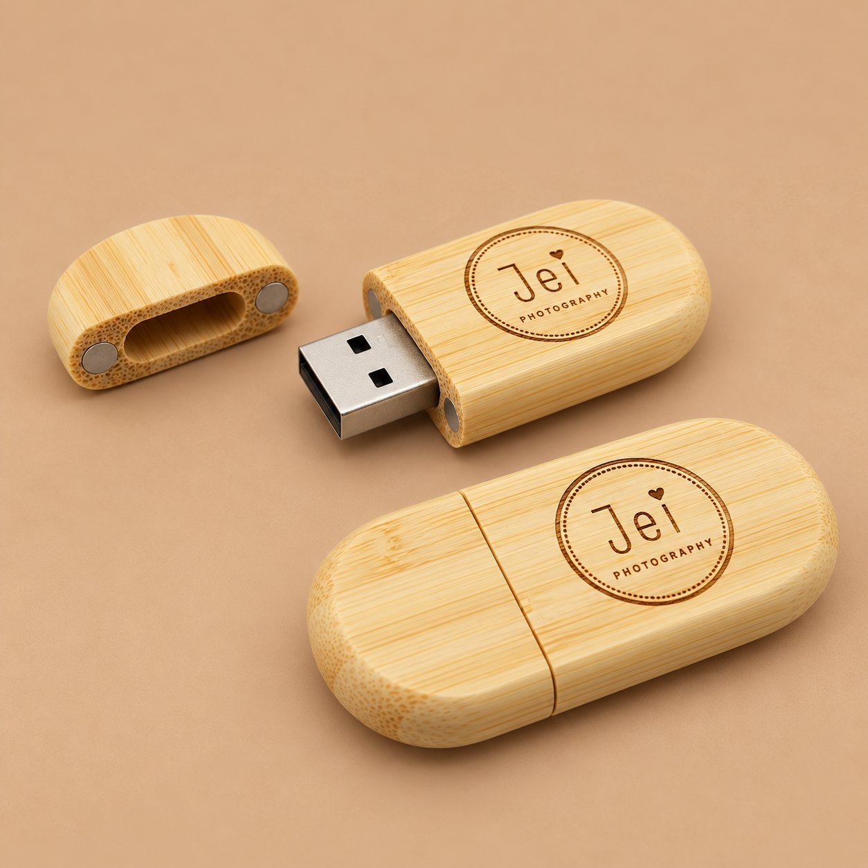 Wooden USB drives engraved with a circular Jei Photography mark and a small PHOTOGRAPHY line beneath, illustrating kerning and small-text legibility.