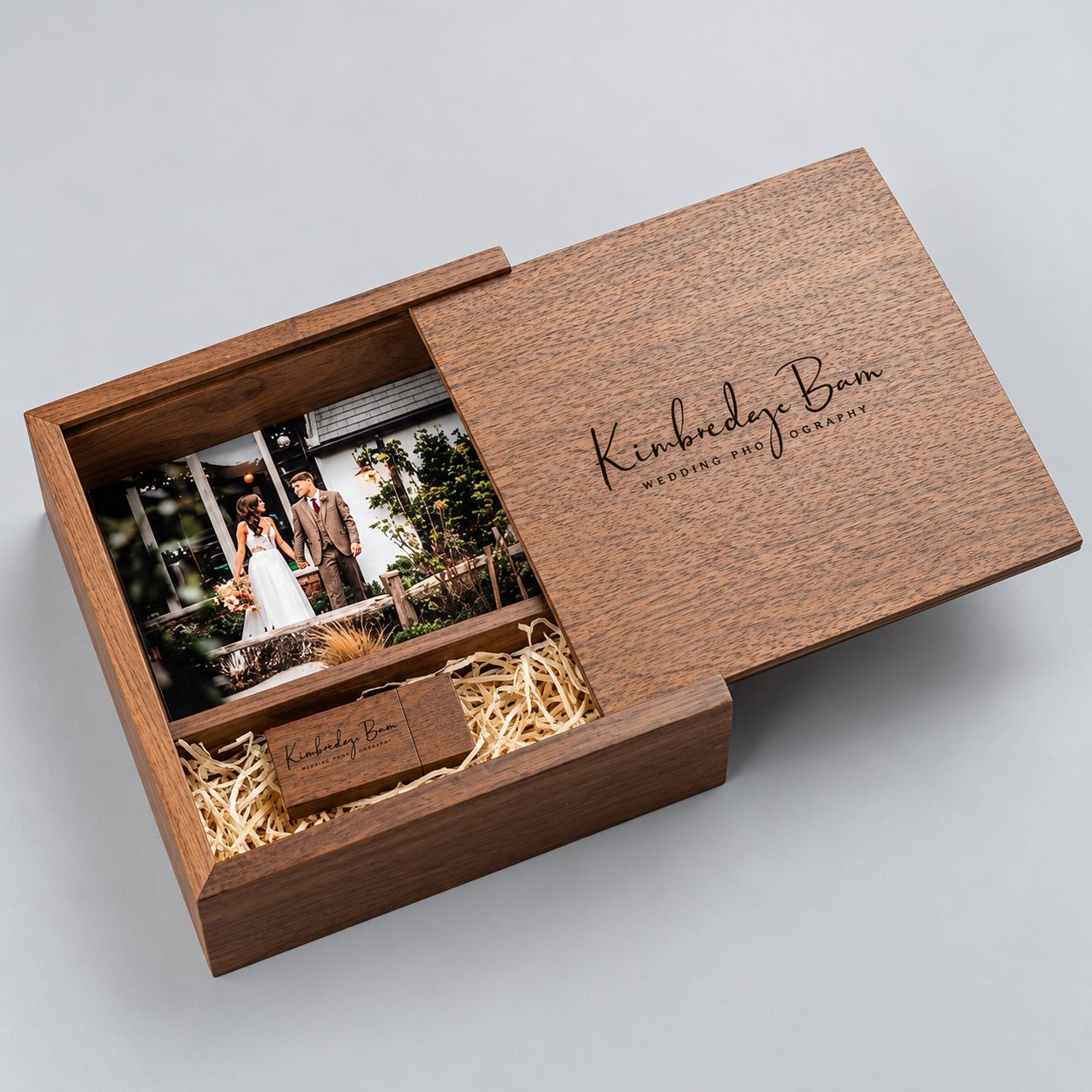 Dark walnut wooden USB photo box with its sliding lid pulled back to reveal a 4x6 wedding photo print of a couple and a custom engraved wooden USB drive tucked into a fitted slot underneath — showing how a sliding-lid wooden box can store both a photo and a USB without an external accessory tray.