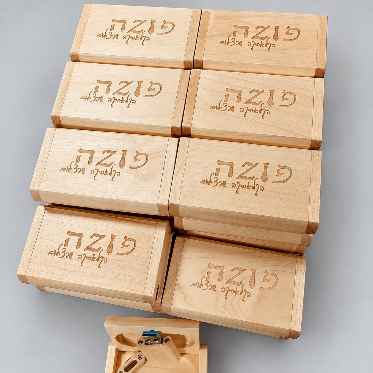 Stack of identical maple wooden USB gift boxes engraved with a custom corporate logo, each individually packaged in protective wrap for bulk shipping to a single client order.