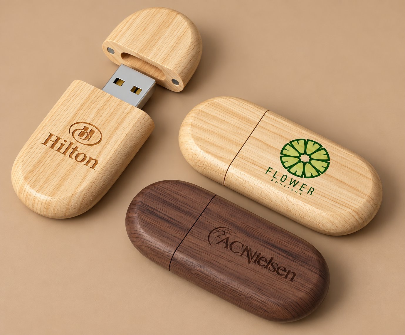 Three branded wooden USB drives engraved with Hilton, Flower Boutique and ACNielsen logos in light maple and dark walnut wood