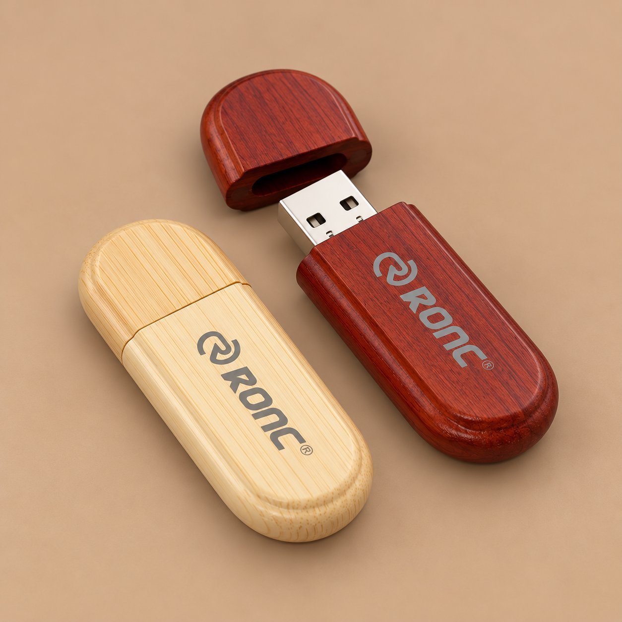 Two wooden USB drives engraved with the Orone logo, one in light maple and one in dark rosewood, showing how the same logo reads on different wood tones