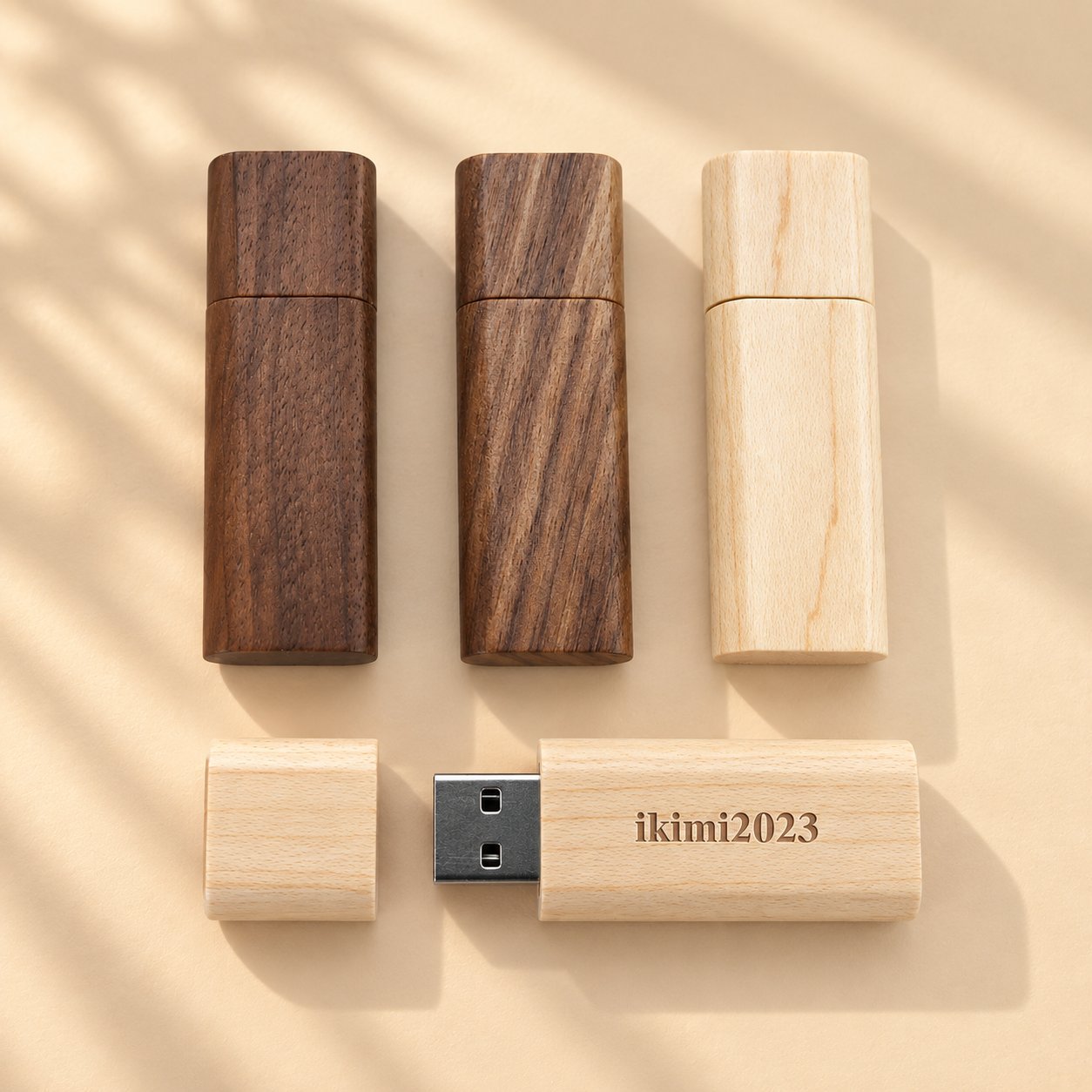 Üç farklı ahşap kaplamada (koyu ceviz, kahverengi ceviz ve açık akçaağaç) dört ahşap USB bellek; ahşap türleri arasındaki doğal dokuyu ve renk varyasyonunu göstermek için özel lazer kazınmış bir adı sergileyecek şekilde biri açılmış.