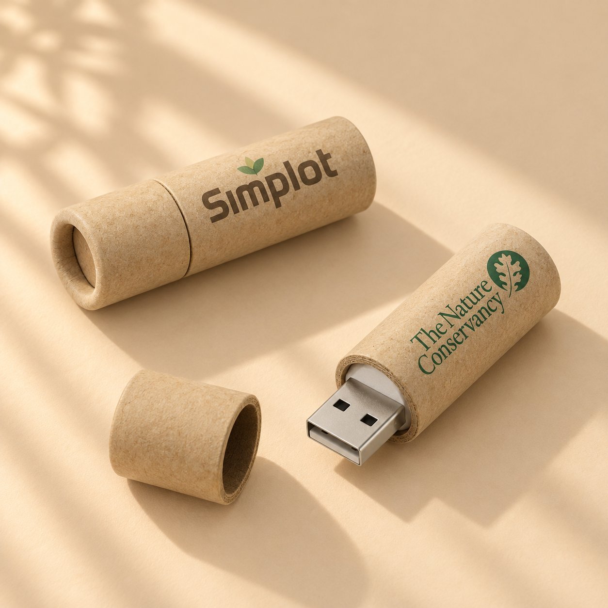 Simplot ve The Nature Conservancy logolarıyla markalanmış iki kraft kağıt tüp USB bellek; geri dönüştürülmüş kağıt bir kasasının çevresel veya sürdürülebilirlik temalı bir kampanya için tam renkli basılı markalamayı nasıl taşıyabileceğini gösterir.