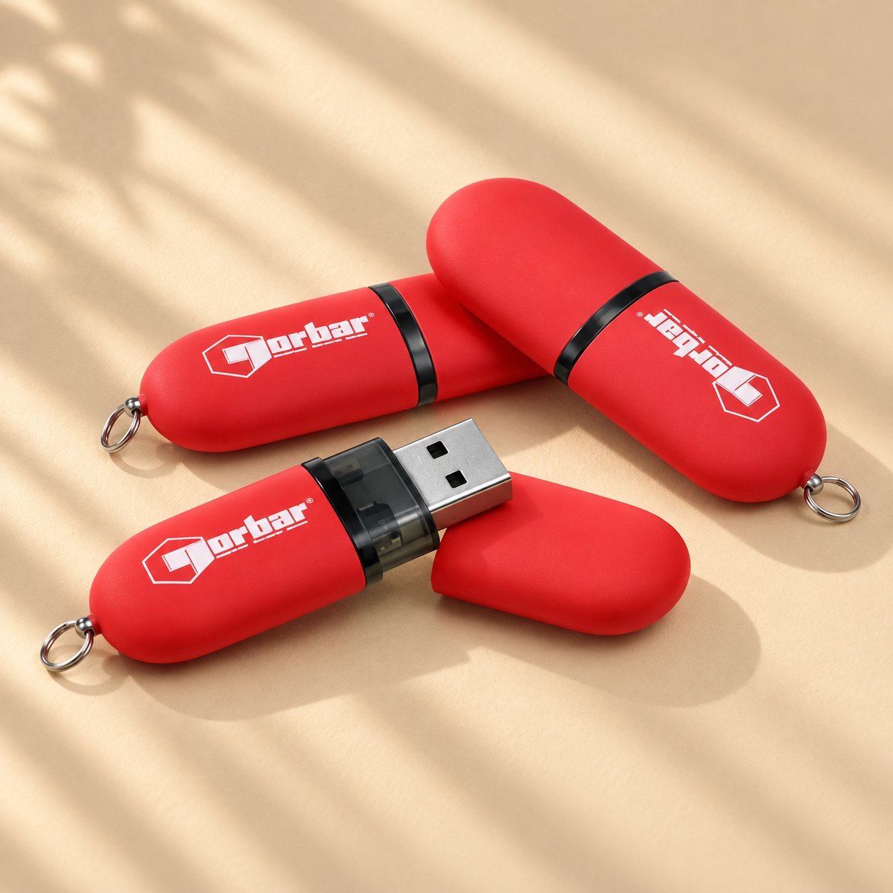 Trois clés USB personnalisées revêtues de caoutchouc rouge estampillées du logo Dorbar, avec des anneaux pour porte-clés, montrant une option de clé typique estampillée clinique médicale ou départementale.