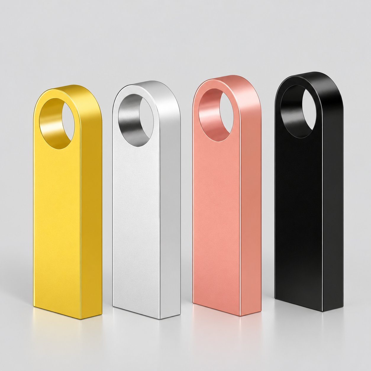 Cuatro memorias USB de metal de barra redondeada con un solo agujero redondo para cordón en amarillo, plata, oro rosa y negro, ilustrando el factor de forma clásico de barra sin tapa que se pide con más frecuencia al por mayor.