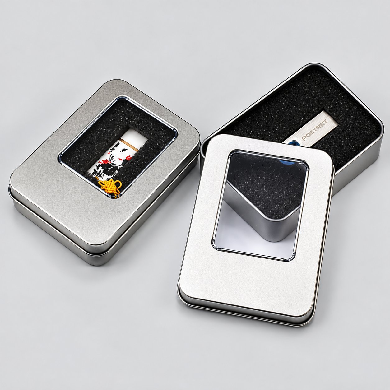 Dos cajas de lata de metal plateadas con insertos de espuma cortados a medida mostrando cómo se ajusta una memoria USB de metal para el tránsito, ilustrando opciones de embalaje protector para envíos al por mayor de USB de metal.