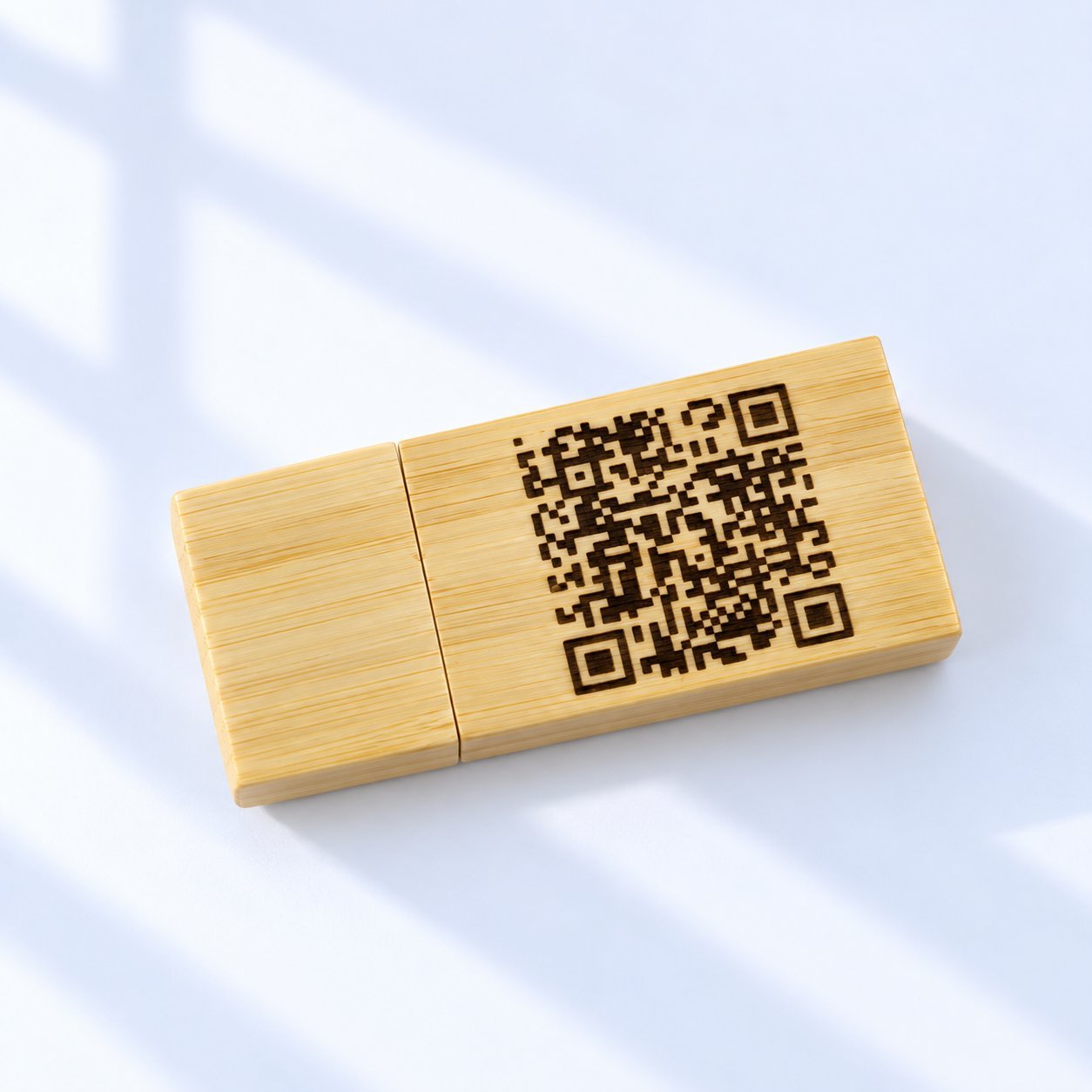 A light bamboo wooden USB flash drive with a dark laser-engraved QR code covering most of its flat body, demonstrating direct engraving on a light wood species where contrast between engraved modules and surrounding bamboo is the limiting factor for scan reliability.