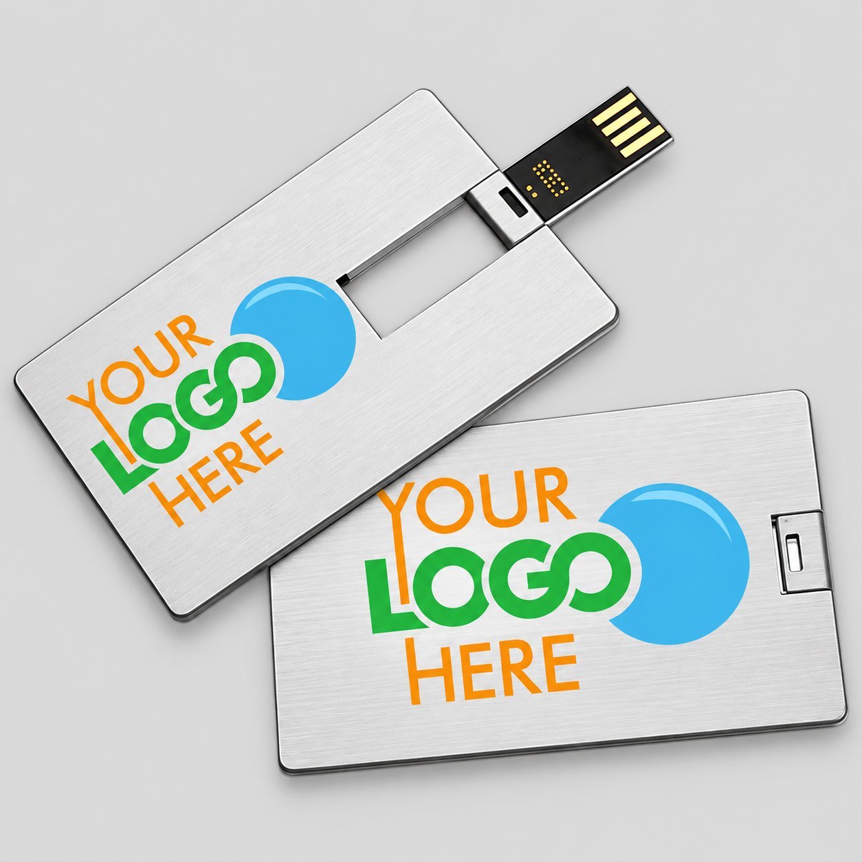 Yeşil, mavi ve turuncu renklerde YOUR LOGO HERE yer tutucu grafiği ile basılmış iki ince gümüş kredi kartı USB sürücü; tam renkli markalama için büyük düz bir baskı yüzeyine sahip kredi kartı form faktörünü göstermektedir.