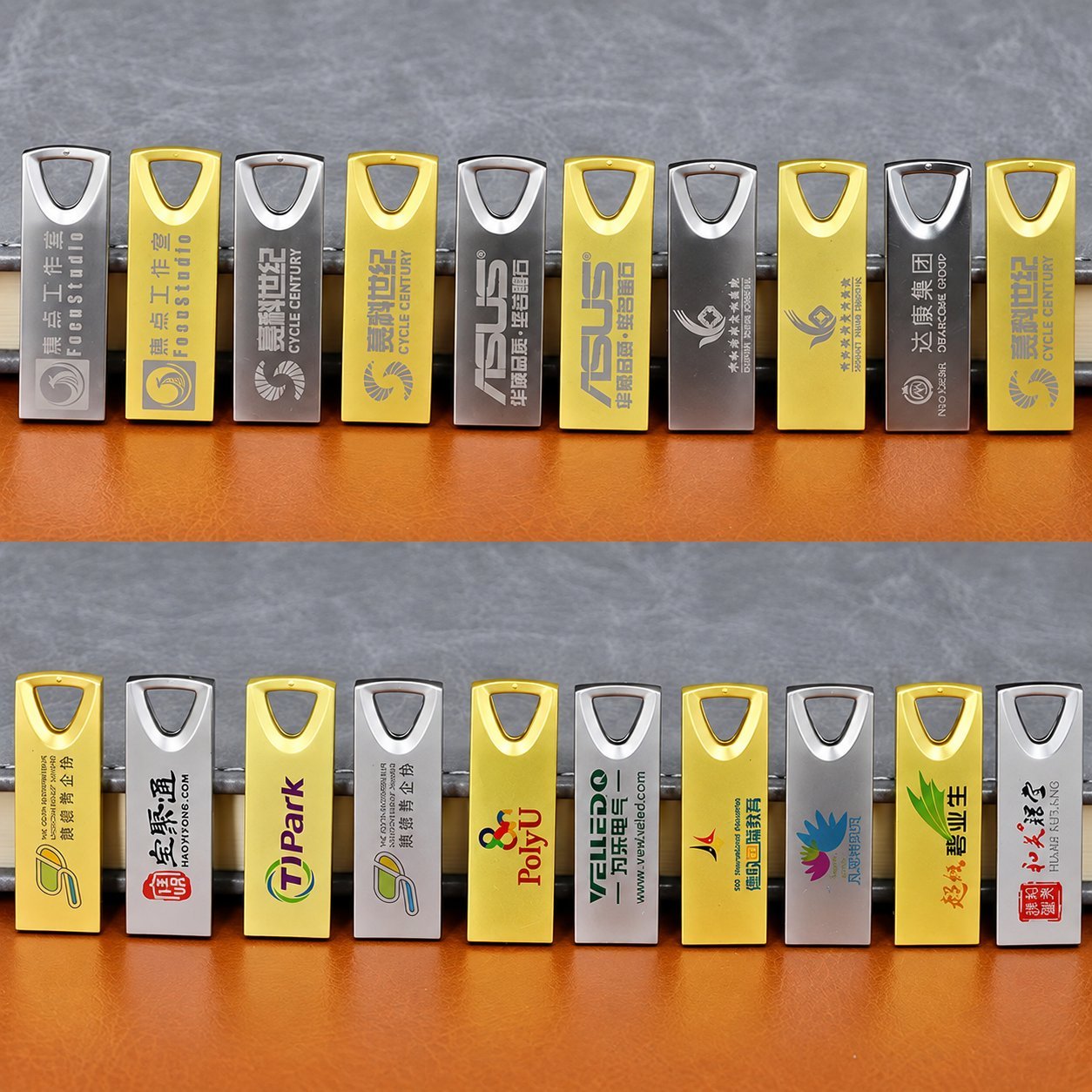 Her biri farklı bir marka adı ve logoyla lazer kazıma yapılmış, üçgen lanyard kesiklerine sahip bir sıra sarı ve gümüş metal USB bellek; bir metal USB gövdesine uygulanan tam renkli ve kazınmış markalama yöntemlerini göstermektedir.