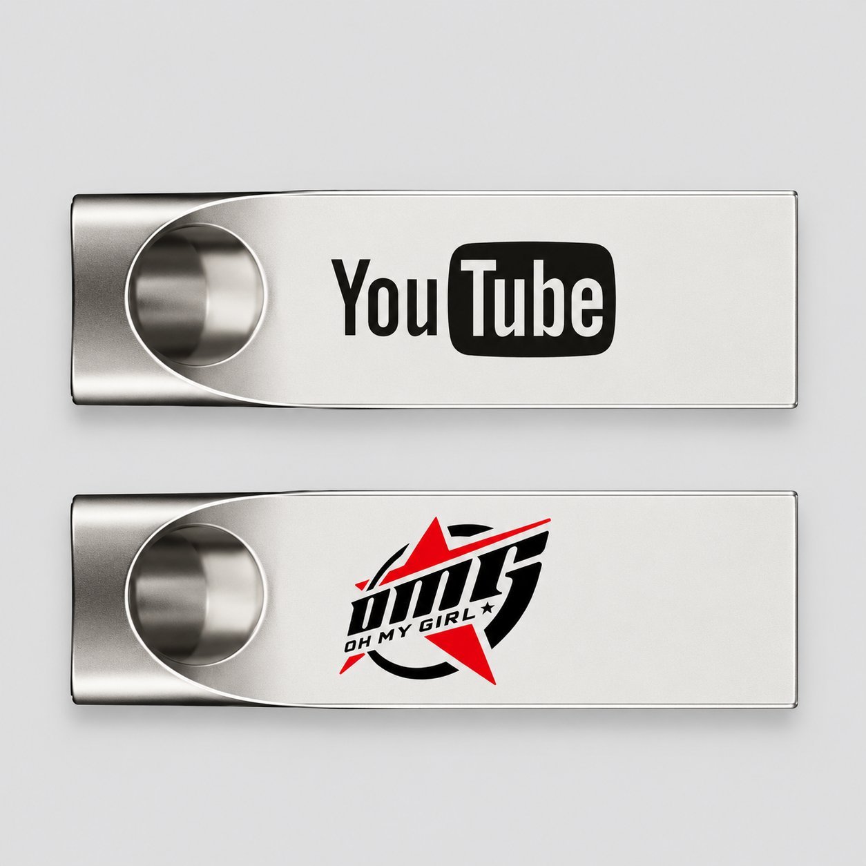 Bir ucunda dairesel kesiklere sahip iki gümüş metal USB bellek; biri YouTube logosu, diğeri OMG OH MY GIRL logosu ile basılmış, bir alıcı markasının metal bir USB üzerinde UV baskı ve lazer kazıma kullanılarak nasıl çoğaltıldığını göstermektedir.