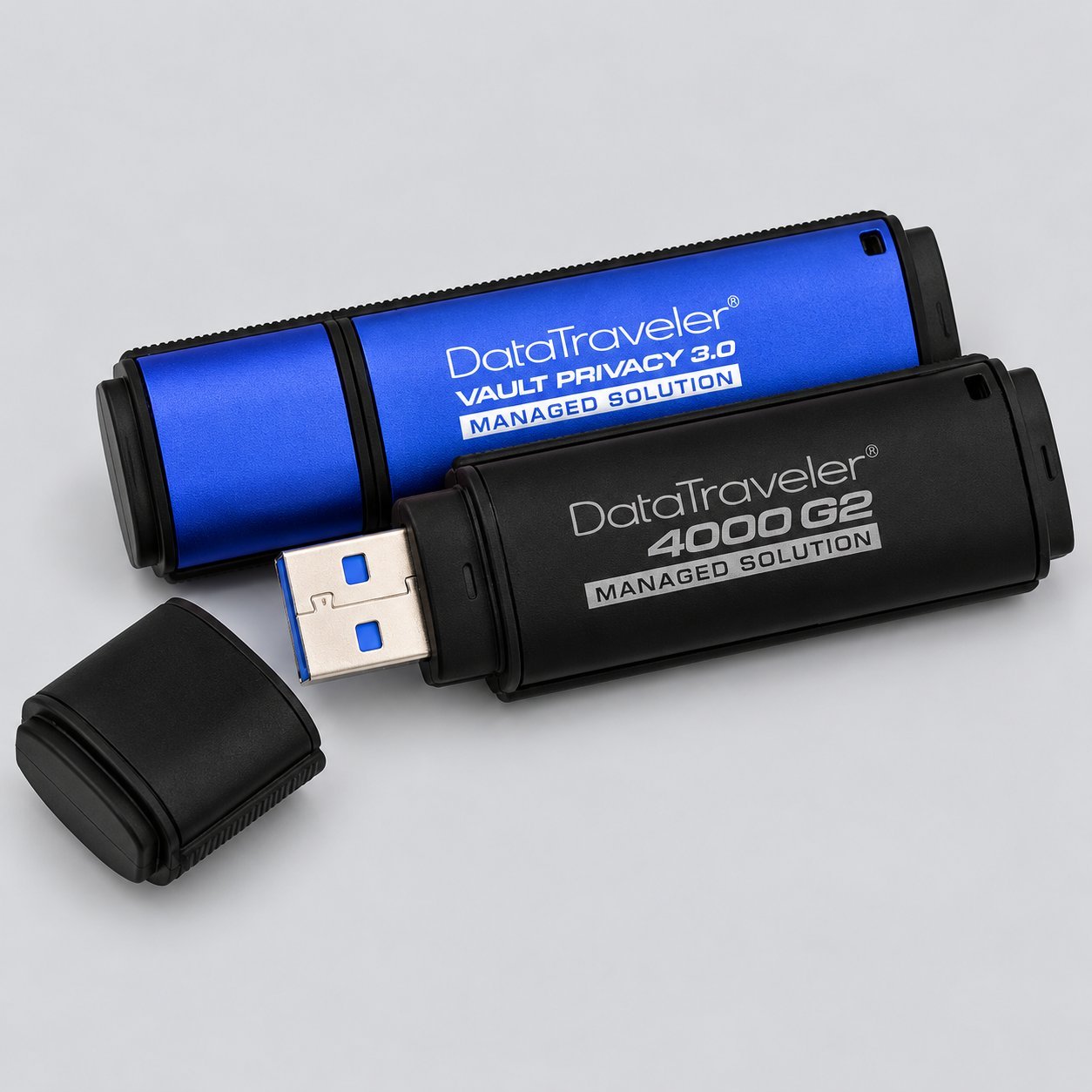 Kapakları çıkarılmış şekilde gösterilen iki Kingston DataTraveler USB bellek — biri mavi Vault Privacy 3.0 Managed Solution, biri siyah 4000 G2 Managed Solution — USB kapasite aralığının yüksek kapasiteli kurumsal ve yönetilen çözüm ucunu gösterir.