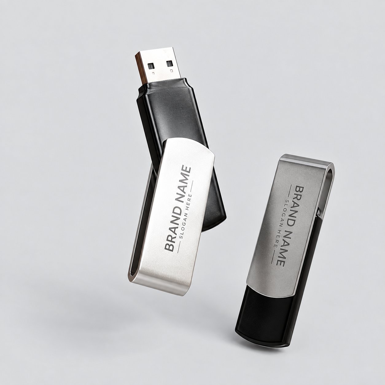 Döner kapağında BRAND NAME ve SLOGAN HERE yer tutucu metni basılı, gümüş ve siyah kaplamalı iki metal döner USB bellek; özel markalı bir metal USB belleğin nasıl yerleştirildiğini ve döner mekanizmanın konnektörü nasıl açığa çıkardığını gösterir.