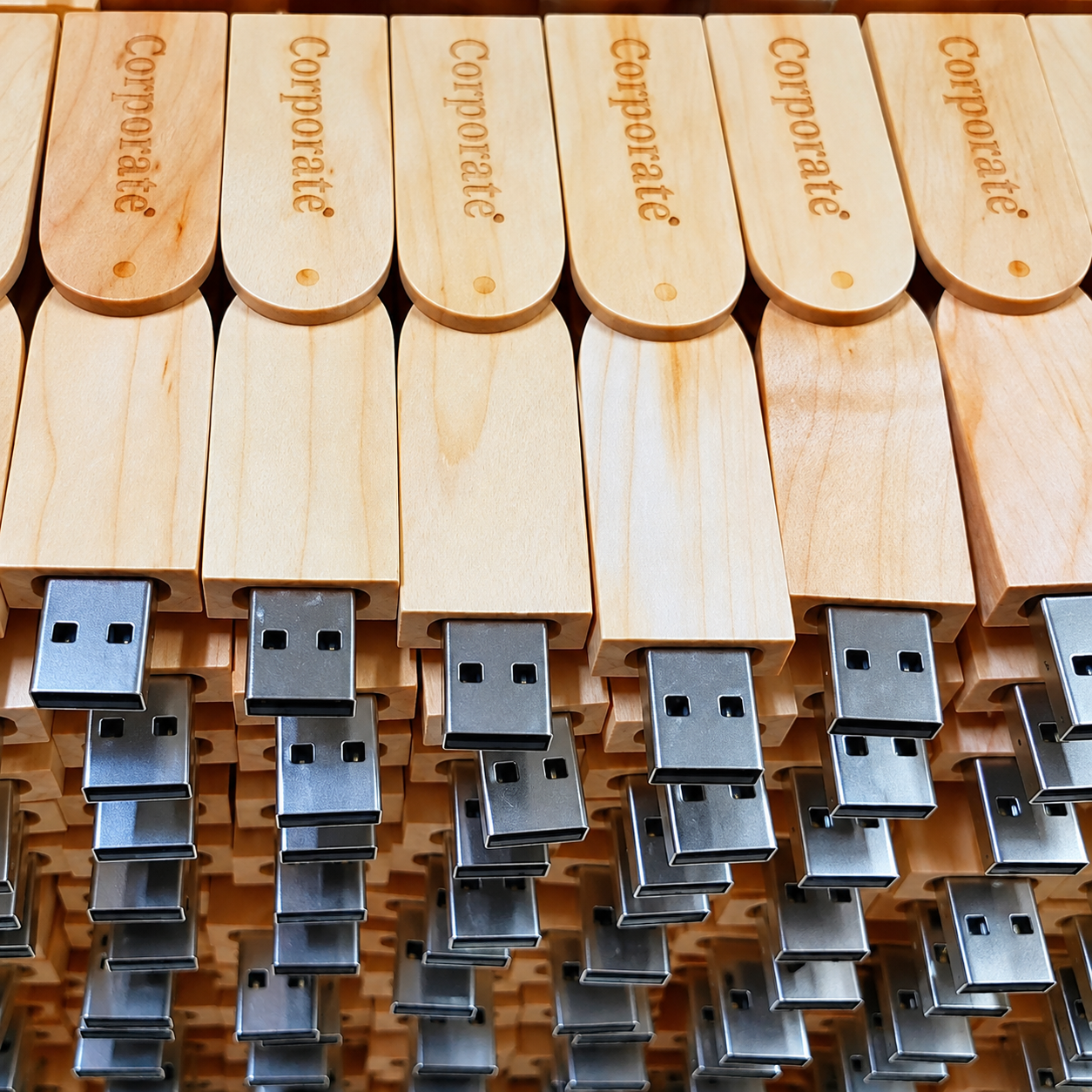 Corporate engraved wooden USB drives arranged in bulk stock